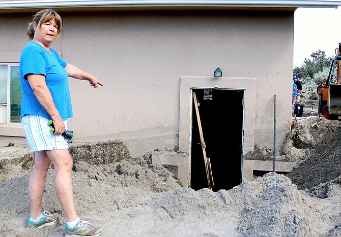 Foothill resident Casey Braun points to where the side door of her home was blown out by 5-6 feet of sand and boulders that washed down into her home.