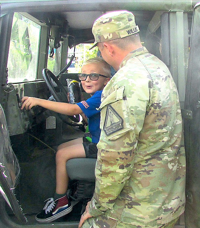 Nevada National Guard Sgt. First Class Gary Willis shows 5-year-old Jameson Tillemans how to turn on a Humvee at the National Night Out
