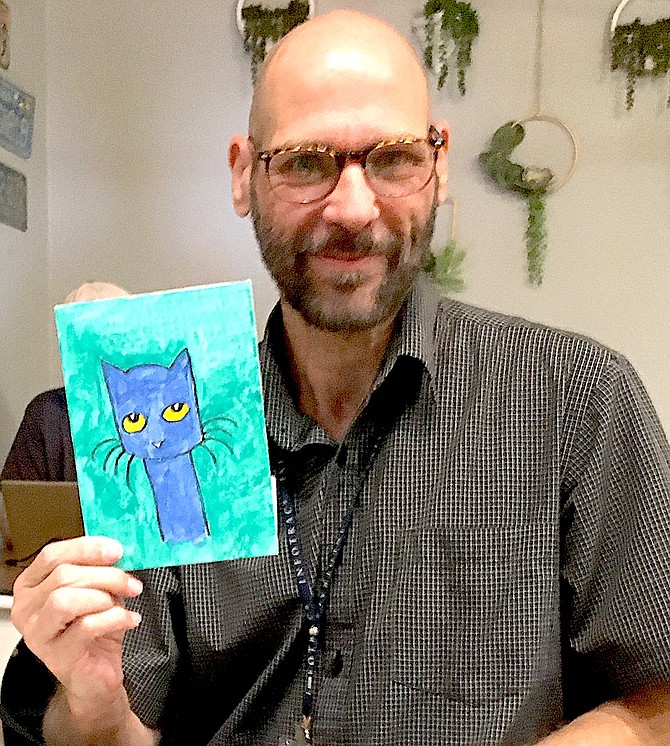 Douglas County Librarian Tim DeGhelder holds up his tiny art piece on Friday.