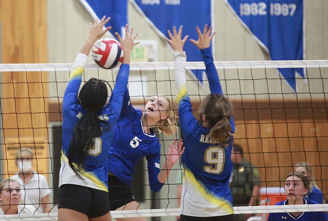Anna Turner puts a kill between two Reed blockers during a match last season. Turner will be a senior with the Senators and is expecting to play a big role in the block for Carson this fall.