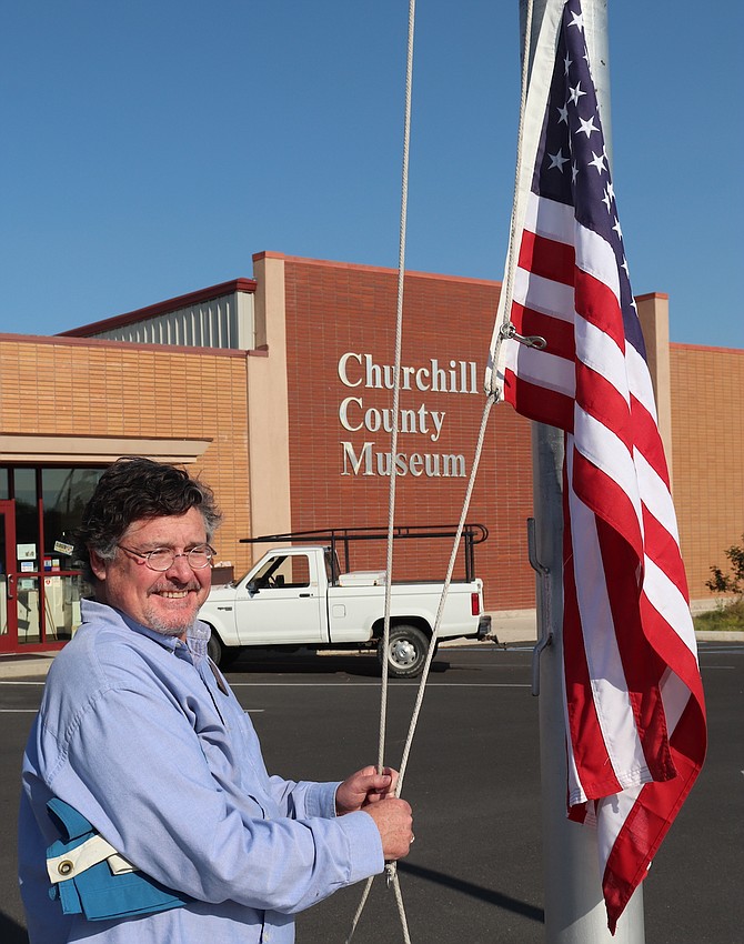 Museum Director Mel Glover raises the flags in front of the museum during his first week.