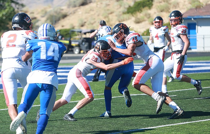 Douglas High's Ryker Rivinius (20) and Cole Smalley (42) combined to make a tackle against a McQueen running back Saturday in Sparks.
