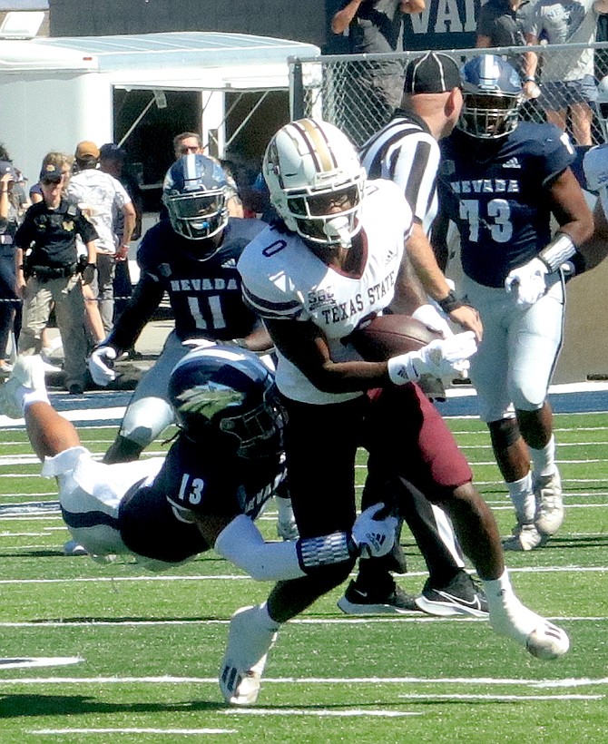 The Wolf Pack’s Zeke Robbins (13) leaves his feet to tackle Texas State’s Rontavius Groves. Nevada won the game, 38-14, at Mackay Stadium.