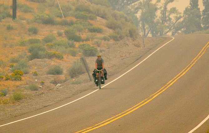 A lone touring cyclist rides south on Foothill Road on Thursday afternoon just as the smoke starts to build to unhealthy levels in Carson Valley.