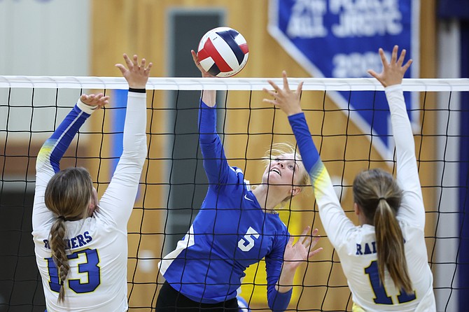 Carson’s Anna Turner with a kill between two Reed players during Tuesday’s game at CHS.