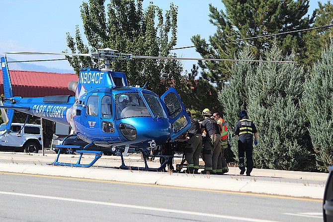 East Fork medics help load a motorcyclist into the Care Flight helicopter that landed on Highway 395 on Thursday afternoon.