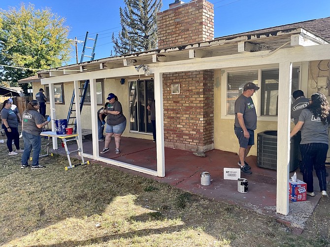 Workers from Lowe’s and Rebuilding Together paint the backside of a Carson City home Oct. 5, 2022.