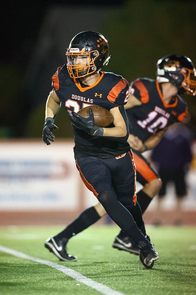 Douglas High running back Andrew Strand (25) takes a carry from Aden Flory (10) for the Tigers Friday night against Spanish Springs.