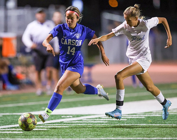 Carson’s Alyssa Tomita dribbles away from a Reed defender during a home game last week. Tomita and the Senators are looking to secure a postseason home game this week as the regular season ends.
