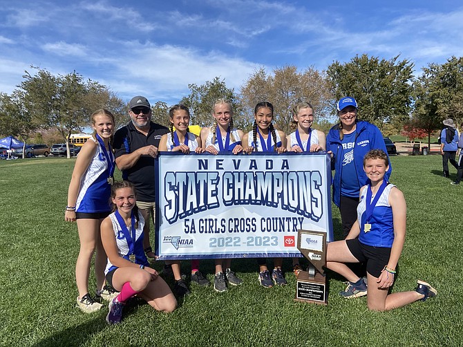 The Carson High girls cross country team poses with the Class 5A state champs banner after winning the girls cross country team title Saturday in Boulder City. Pictured in front from left to right are Jinnie Ponczoch and Eleanor Romeo. In back, are Sydney Romeo, head coach Jason Macy, Hannah Budd, Vea Miner, Brianna Rodriguez-Nunez, Madison Hager and assistant coach Janie Davis