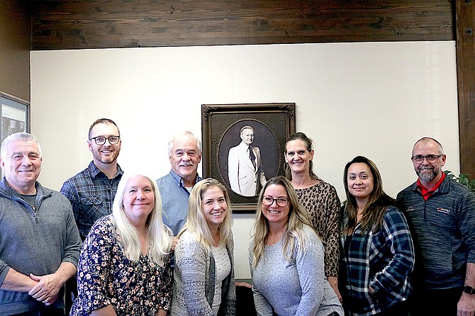 Warren Reed Insurance team at the Gardnerville office Mike Downs, Taylor Reed, Carolyn Mitchell, Alan Reed, Rachel Rodriquez, Kristy Glover, Shannon Minder, Celeste Covey and Jeff Long pose with portrait of founder Warren Reed. Not pictured: Todd Wilks, Jim Norton, Ben Reed and Robin Frediani.