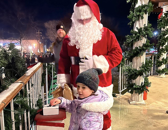 Seven-year-old Ainsley Rasmussen throws the switch at the Minden Gazebo lighting with some guidance from Santa.