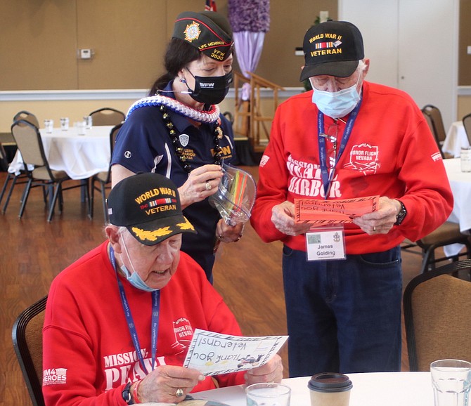World War II veterans John Glimmerveen, left, and James Golding, read letters at the Veterans of Foreign Wars in Honolulu in 2021. With them is Debra Lewis, commander of the VFW in Hawaii.