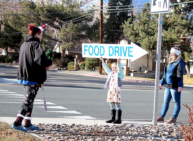 Six-year-old Dayton resident Saffyre Cobb holds up the Food Drive sign along Highway 395 at the Carson Valley Inn on Friday.