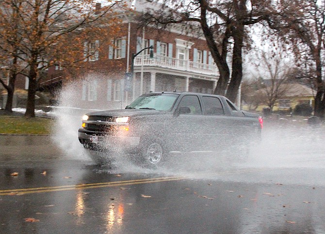 A vehicle splashes through water ponding on Main Street near the Genoa Courthouse Museum on Tuesday morning.