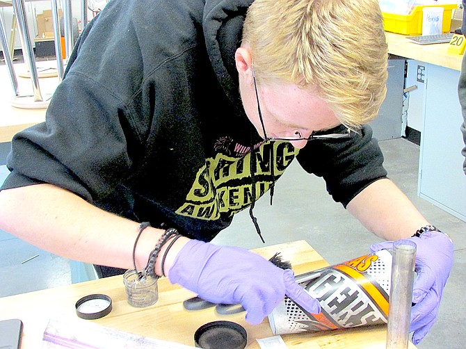 Junior Phoenix Berke removes fingerprints from a mug found at the scene of the mock homicide in Kimberly Tretton’s Forensics class Wednesday.
