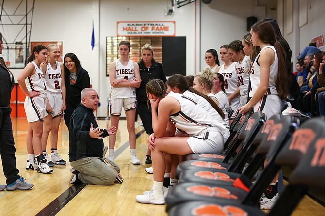 The Douglas High girls basketball team surrounds head coach Jason Carter during a timeout Tuesday. The Tigers got off to a fast start and defeated Reed, 58-36.