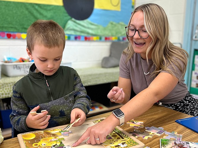 Carson City School District kindergarten teacher Heather Canfield assists on a puzzle with one of her students.