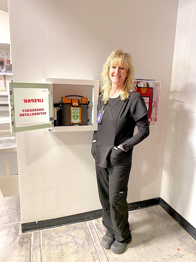 Douglas High School Nurse Jennifer Hinnant next to a new AED.