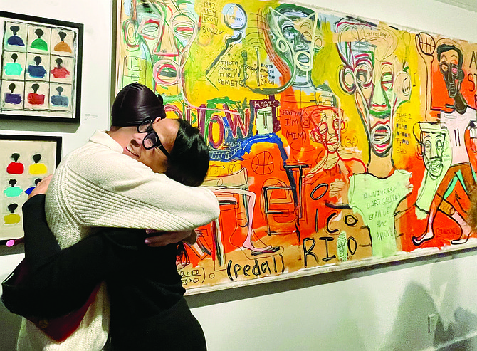 Queen Anne artist Xavier Kelley, left, receives a hug from Domicile art gallery owner Marisa Spooner-LeDuff while standing next to one of his pieces at an artist reception celebrating Black History Month at the gallery in Madison Park on Feb. 10.