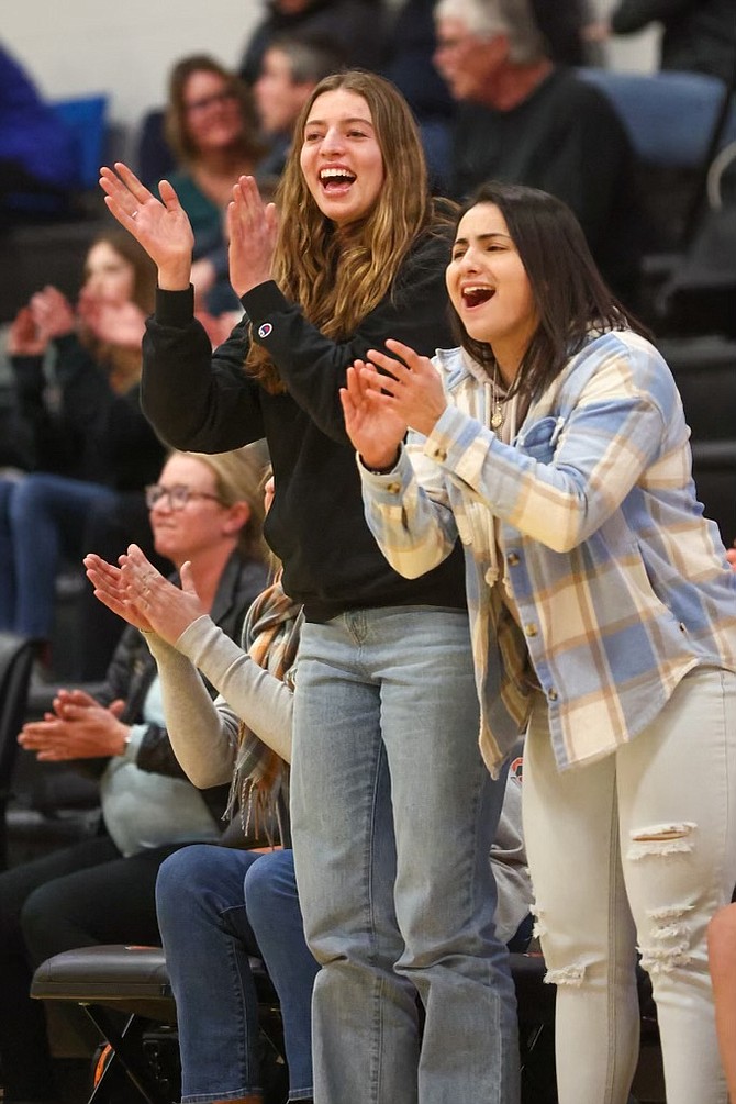 Douglas High senior and assistant coach Camden Miller, left, applauds the Tigers alongside assistant coach Karla Sanchez, during a regular season basketball game this past winter. Miller missed her senior season while recovering from a torn ACL suffered during soccer season.