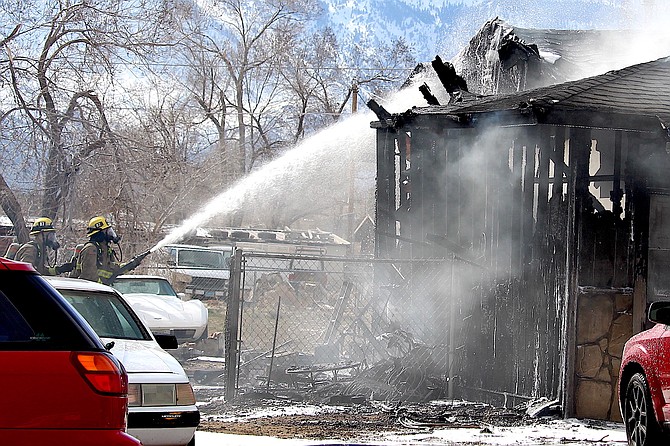 Firefighters spray down a home on fire in the Gardnerville Ranchos on Tuesday afternoon.