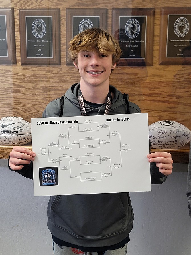 Jaden Allec, an eighth grader from Eagle Valley Middle School, poses with his bracket after winning the 120-pound weight class championships at Pershing County High School.
