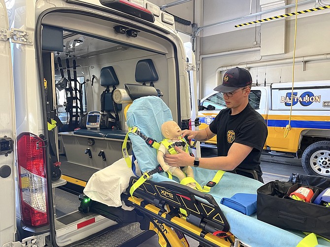 CCFD BLS Technician Jacob O’Brien buckling in a doll to demonstrate new pediatric restraints at Fire Station 51 on April 14.