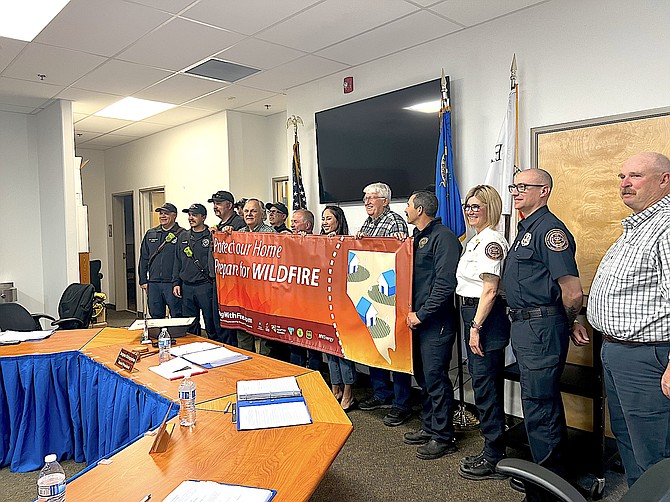 East Fork Fire Protection District Board trustees, firefighters and supporters hold up a banner encouraging wildfire awareness as part of the Nevada Wildfire Awareness Campaign.