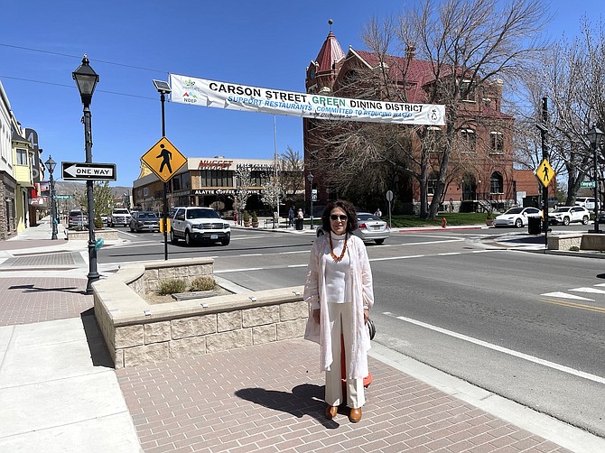 Donna Walden of greenUP! — organizer of the Carson City Green Dining District — beneath a promotional banner over Carson Street on April 24.