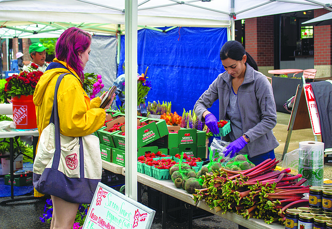 An employee at Sidhu Farms helps a customer at last year’s Queen Anne Farmers Market. Sidhu Farms will return as one of 28 vendors selling farm products, which also includes ranchers and fishermen.