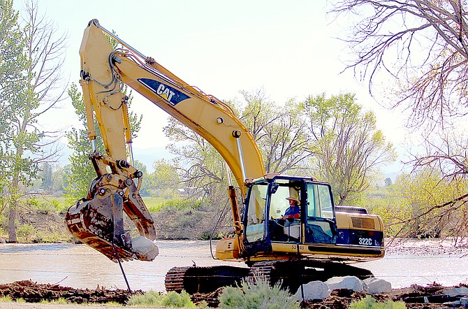 An excavator is moving boulders onto the banks of the East Fork upstream from the Highway 88 bridge on Friday morning.