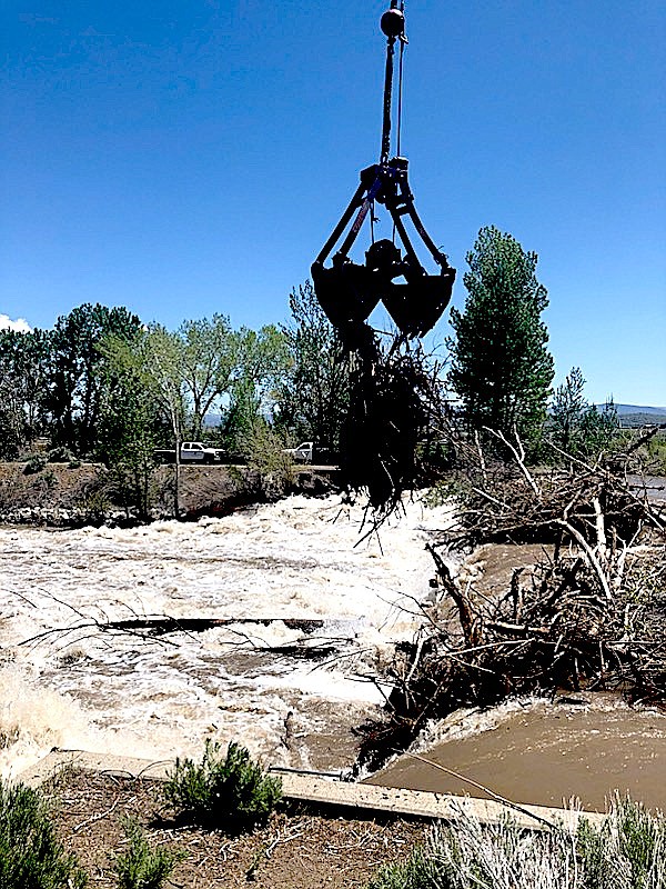 Logs and debris are lifted away from a logjam at the Virginia-Rocky Slough diversion on the East Fork of the Carson River by Connelly Crane.