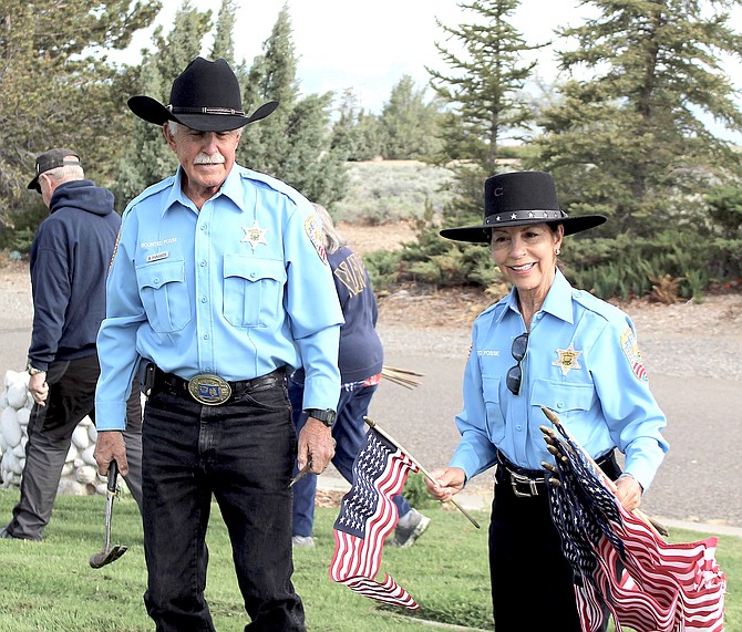Posse members Guy Sapp and Christine Blackburn place flags in Eastside Memorial Park in Minden on Friday morning.