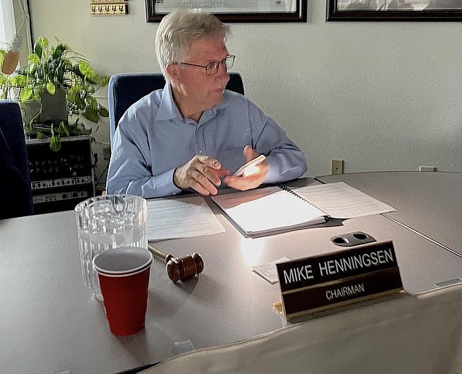 Gardnerville Town Board Chairman Mike Henningsen uses the flashlight on his phone to read the agenda after power was lost to Gardnerville on Tuesday.