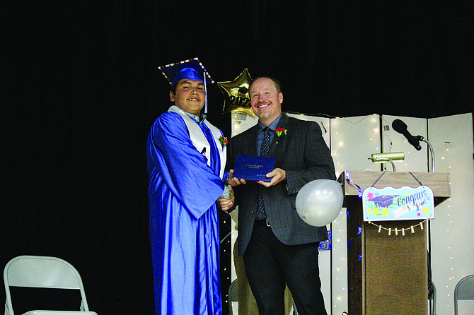 Humboldt County Superintendent Dave Jensen hands Elias Smart his diploma.