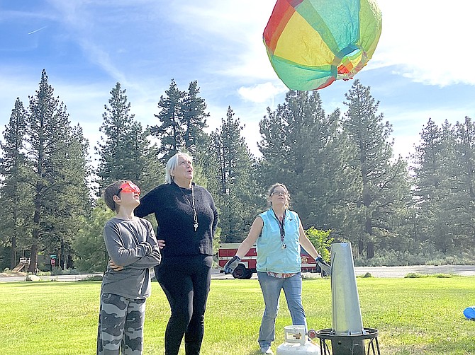Diamond Valley student Elliot, Interim Principal Annie Millar and teacher Jennifer Munyan launch a tissue paper balloon in Woodfords as part of a lesson on flight.