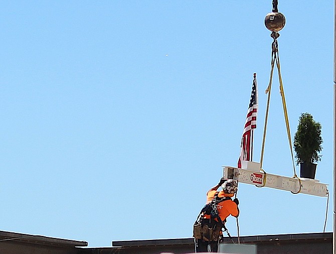 An iron worker guides a beam with the signatures into place at Carson Valley Health on Friday morning.