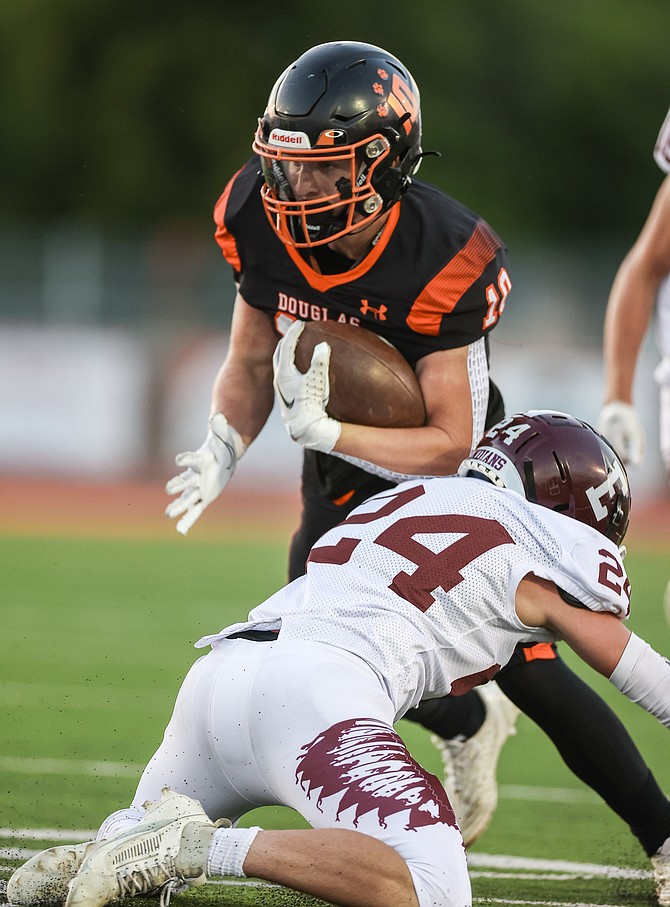 Douglas High’s Andrew Strand (10) lowers his shoulder to get around an Elko defender Friday night in the Tigers’ 14-9 home win. Strand had eight carries for 45 yards in the win.