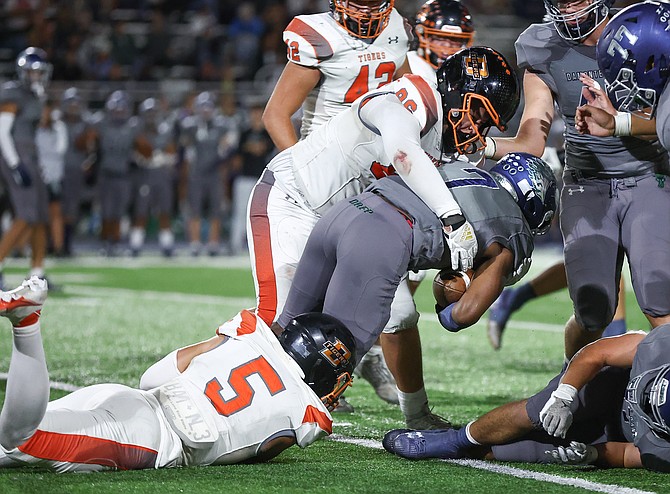 Douglas High’s Nathan Stevens (86) and Zachary Westbrook (5) combine to stop a Damonte Ranch ball carrier Friday. The Tiger defense allowed seven points against the Mustangs and is giving up an average of four points per game.