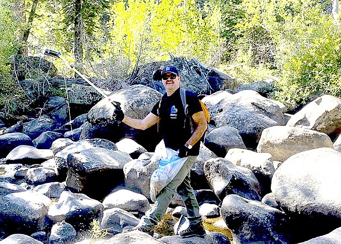 A volunteer helps pick up trash in Woodfords Canyon as part of the Great Sierra River Cleanup at Creek Day 2022.
