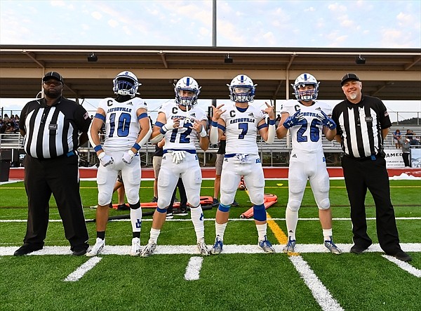 Eatonville senior captains Max Henley (#10), Riley Storm (#12), Payton Hanly (#7), and Dylan Norman (#26) pose with a few of the officials prior to the pregame coin toss this past Saturday evening.