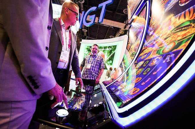 G2E attendees test an IGT gaming machine at the company's trade show booth during the conference on Tuesday, Oct. 11, 2022.