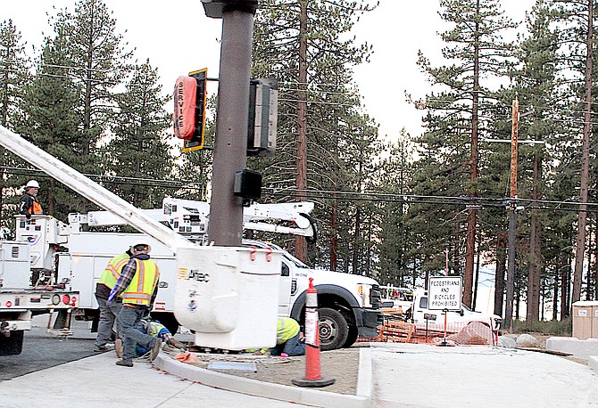 Workers install the traffic signal at Warrior Way early Thursday morning.