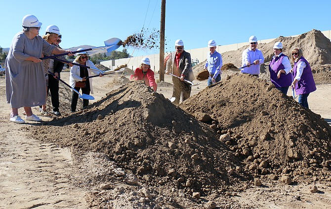 Carson City officials, including Mayor Lori Bagwell and Supervisor Stacey Giomi, center, representatives from general contractor Shaheen Beauchamp Builders LLC and Advocates to End Domestic Violence staff members toss dirt at AEDV’s groundbreaking for its shelter Wednesday.