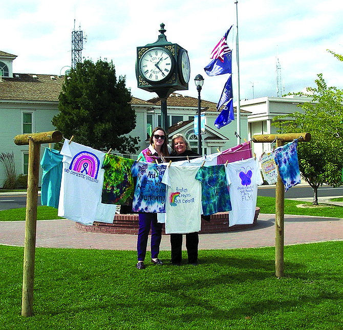 Carin Gomes and Karen Moessner of Domestic Violence Intervention Fallon stand with shirts displayed on “The Clothesline Project” at Millennium Park.