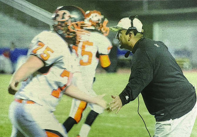 Former Douglas High School football head coach Ernie Monfiletto high fives a Douglas player during a game.