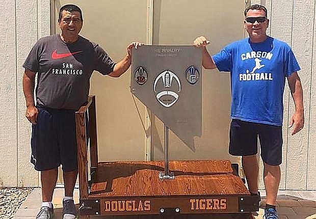 Former football coaches Ernie Monfiletto (Douglas) and Blair Roman (Carson) stand next to The Rivalry Trophy in 2017 after its creation.