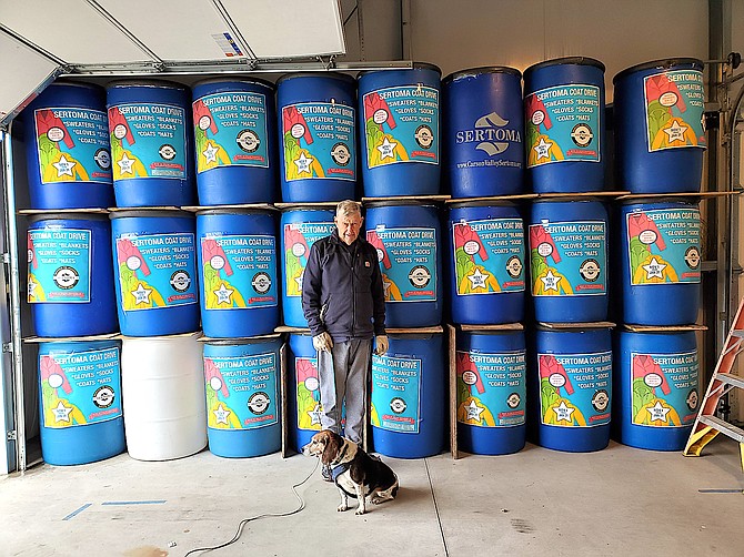 Doug Behr and Harley the Beagle in front of all the Sertoma coat drive barrels. Photo special to The R-C by Eileen Behr