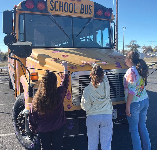Students place purple handprints on a Churchill County School District bus in recognition of Domestic Violence Awareness Month.